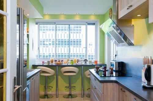 une cuisine avec un comptoir avec des tabourets et une fenêtre dans l'établissement Chambre d'hôtes Au Coeur De NancyB&B, à Nancy
