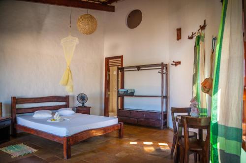 een slaapkamer met een bed, een tafel en een stoel bij Casa Cumbuco e Hospedaria in Cumbuco