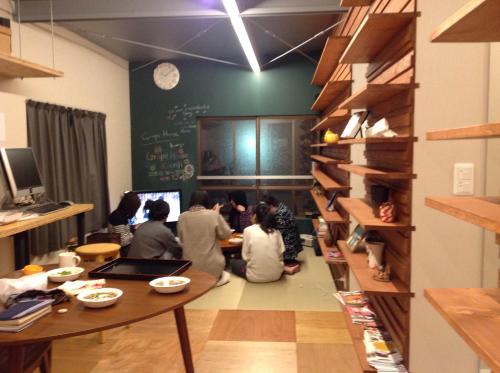 un grupo de personas sentadas en una mesa en una habitación en GrapeHouse Koenji en Tokio