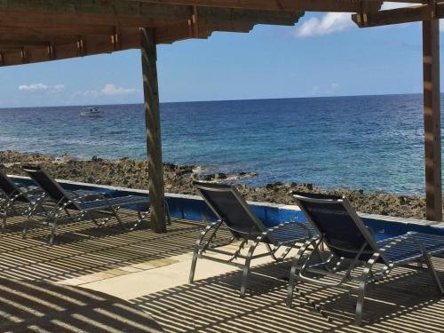 a row of chairs sitting on a deck near the ocean at Lands End in West End