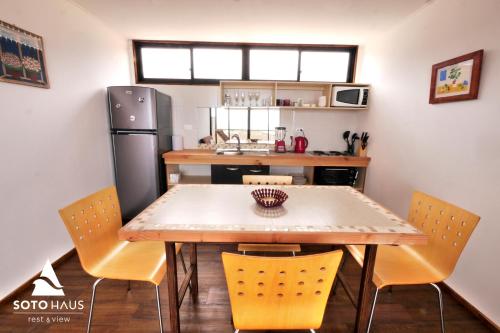 a kitchen with a table and chairs and a refrigerator at SOTO HAUS Totoralillo Mar in Totoralillo