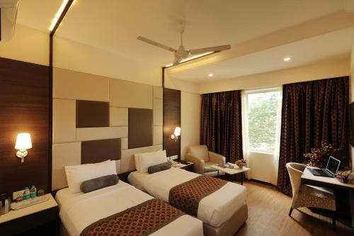 a hotel room with two beds and a desk at Hotel Pai Vista in Mysore