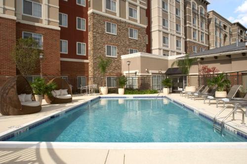 a swimming pool with chairs and a building at Hyatt House Sterling/Dulles Airport North in Sterling