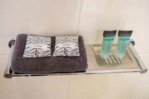 two towels and toothbrushes on a glass shelf in a bathroom at Highway Inn Motel in Hay