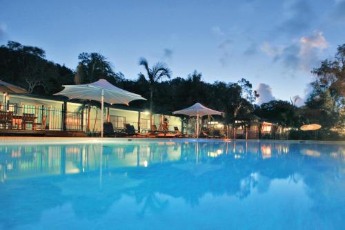 ein großer Pool mit Sonnenschirmen vor einem Gebäude in der Unterkunft Angourie Resort in Yamba