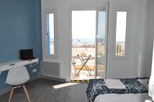 a bedroom with a bed and a balcony with a table at Hôtel de la Mer in Valras-Plage