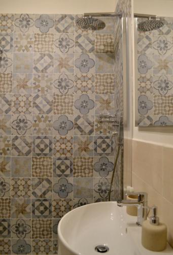 a bathroom with a white sink and a tiled wall at Domus Duomo in Florence