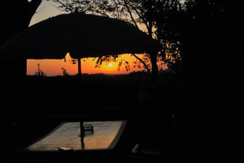 a silhouette of a table with an umbrella at sunset at Borgo La Casaccia in Montaione