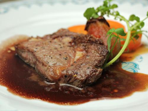 a piece of steak on a plate with sauce at Pension Raisin in Kusatsu