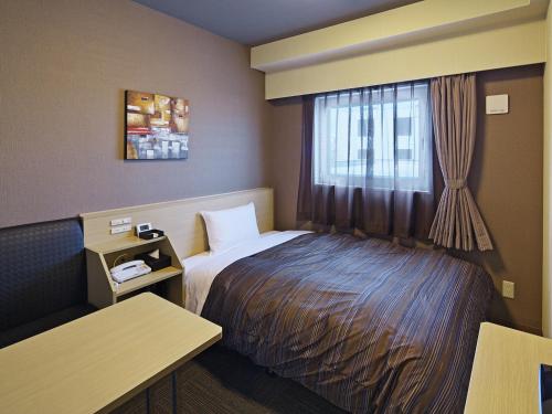Hotel Route Inn Hitachinaka في هيتاتشي-ناكا: غرفه فندقيه بسرير ونافذه