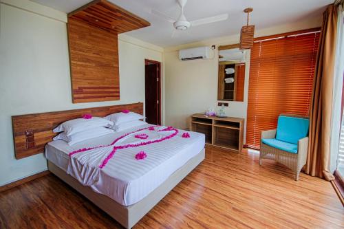 a bedroom with a large bed and a blue chair at Kinan Retreat in Fulidhoo