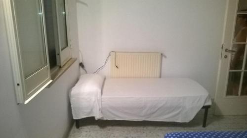 a white bed in a room with a chair at casetta cassia roma in Isola Farnese