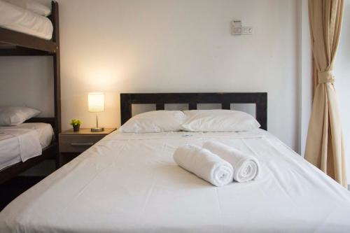 a white bed with two rolled towels on it at Casa Villamor in Máncora