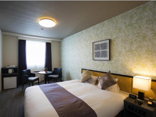 a hotel room with a bed and a table with chairs at Hotel La'gent Plaza Hakodate Hokuto in Hokuto