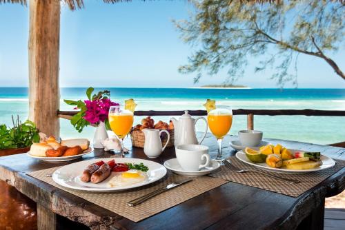 a table with plates of breakfast food on the beach at Sunshine Marine Lodge in Matemwe