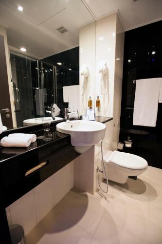 a bathroom with a sink and a toilet and a mirror at Holiday Bahrain Hotel in Manama