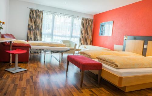 a room with four beds and a red wall at Hotel Blattnerhof in Blatten bei Naters