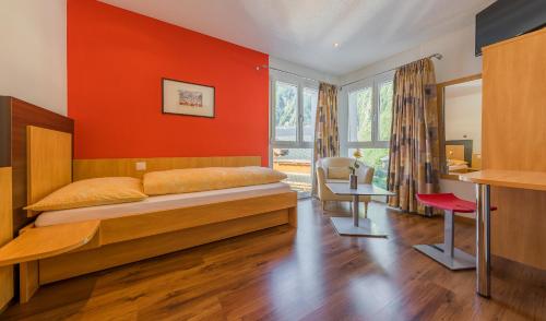 a bedroom with a bed and a red wall at Hotel Blattnerhof in Blatten bei Naters