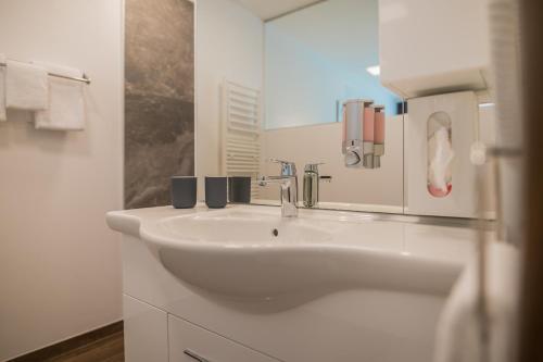 a white bathroom with a sink and a mirror at Hotel Blattnerhof in Blatten bei Naters