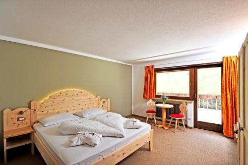 a bedroom with a large bed and a large window at Hotel Gerstgras in Maso Corto