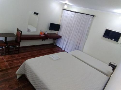 um quarto com uma cama, uma mesa e um espelho em Hotel Lago Azul em Louveira