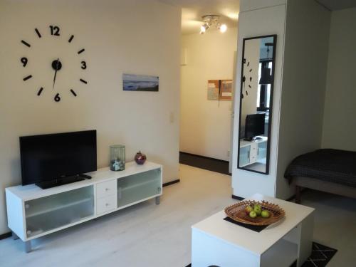 een woonkamer met een tv en een klok aan de muur bij A lovely one-room apartment near the city centre. in Vaasa