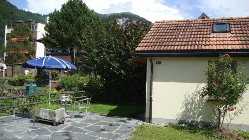 ein kleines Haus mit einem Tisch und einem Sonnenschirm in der Unterkunft Montanara in Meiringen