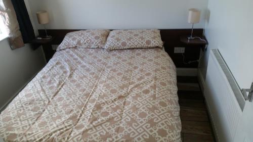 a bedroom with a bed with a comforter and two pillows at Noirin's Holiday Homes in Falcarragh