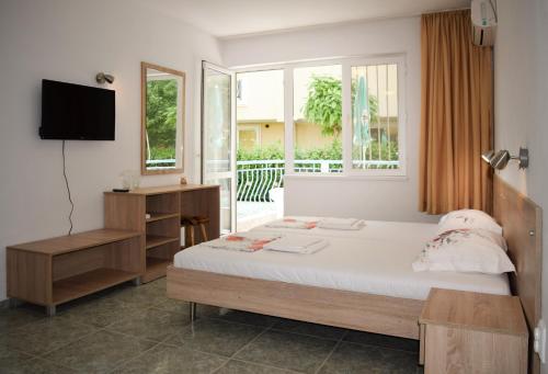 a bedroom with a bed and a tv and a window at Stella di Mare Guest House in Ravda