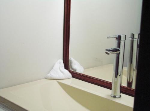 a bathroom sink with a mirror and a faucet at Hotel Inn Plaza del Ángel Chihuahua in Chihuahua