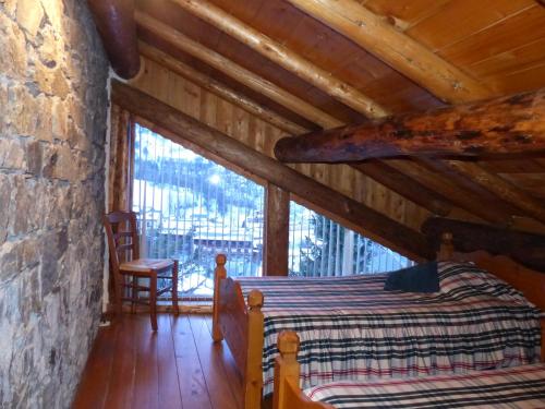 ein Schlafzimmer in einem Blockhaus mit einem Bett und einem Fenster in der Unterkunft Appartement cosy pour 4 personnes en chalet de pierres in Saint-Martin-de-Belleville