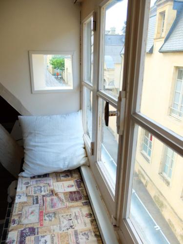 Cette chambre dispose de 2 fenêtres et d'un oreiller à côté d'une fenêtre. dans l'établissement Chez Titi, à Bayeux