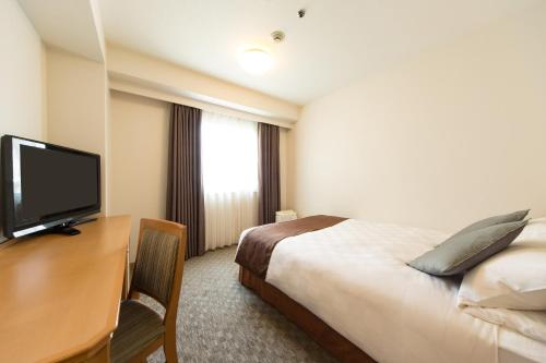 a hotel room with a bed and a desk with a television at Osaka Tokyu REI Hotel in Osaka