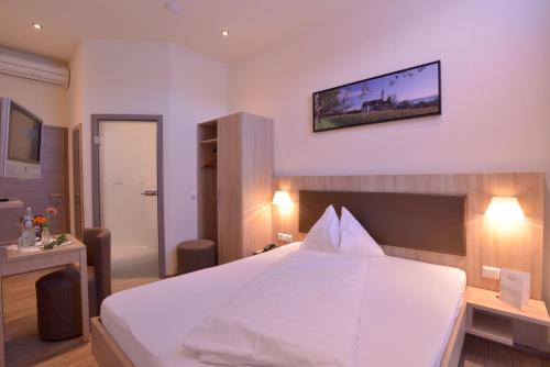 a bedroom with a white bed and a tv on the wall at Gasthof Ziegler Hotel & Restaurant in Lindau