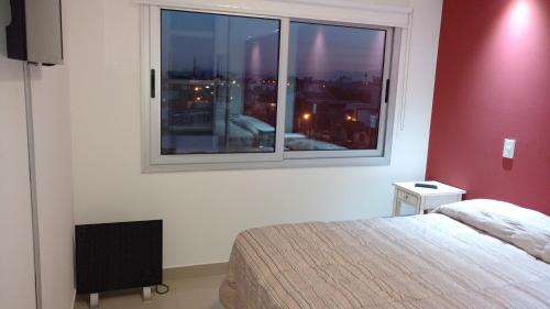 1 dormitorio con cama y ventana grande en Alvarado Departamentos en Salta
