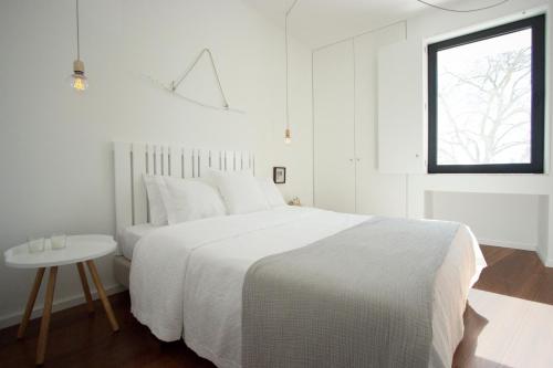 a white bedroom with a white bed and a window at Casa dos Aromas in Évora