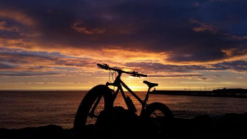 a bike parked on the beach with the sunset in the background at Hilltop Seaview Apartment in Wicklow