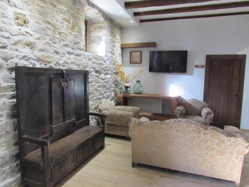a living room with couches and a stone wall at Txantxorena in Zubiri