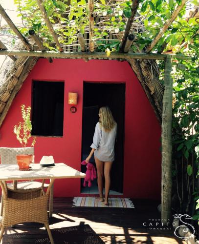 a woman standing in the doorway of a red house at Pousada Capitù in Imbassai