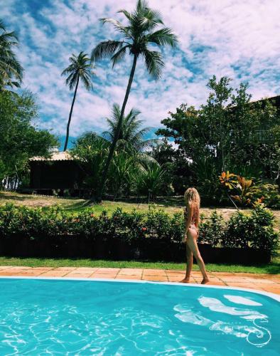 a woman in a bikini walking into a swimming pool at Pousada Capitù in Imbassai