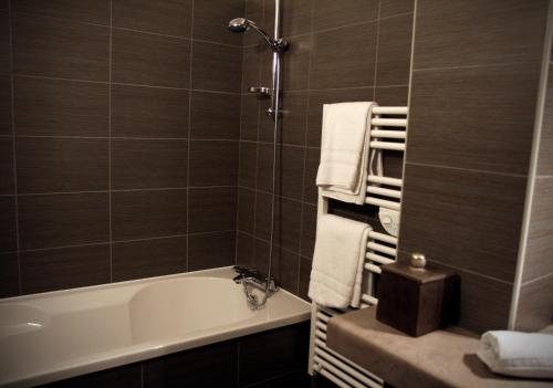 a bathroom with a tub and a shower with towels at Hôtel Bar le Globe in Saint Die
