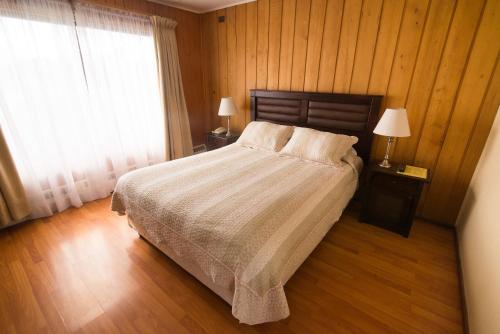 a bedroom with a bed and two lamps and a window at Hotel Terrazas del Lago in Puerto Varas