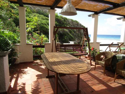 a patio with a table and chairs and the ocean at Villa la Ficuzza in Cittadella del Capo