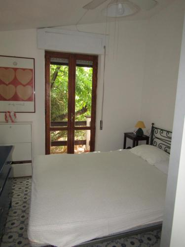 a bedroom with a white bed and a window at Villa la Ficuzza in Cittadella del Capo