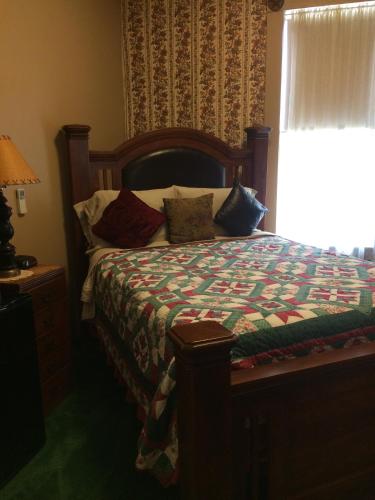 a bedroom with a bed with a quilt and a window at The Courtland Hotel & Spa in Fort Scott