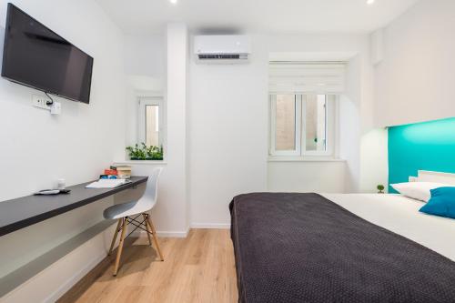 a bedroom with a bed and a desk and a tv at Flumen in Rijeka