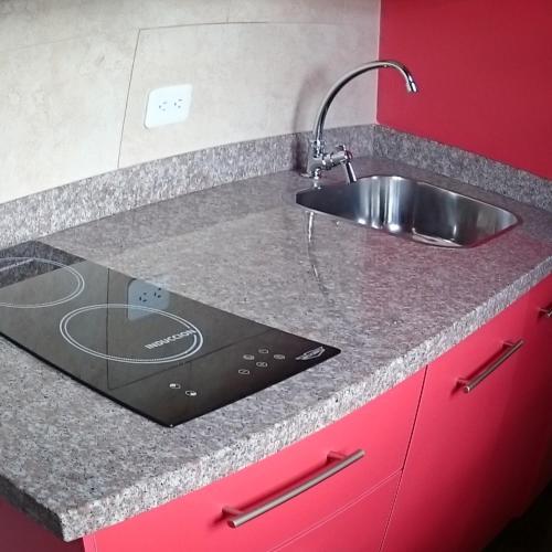 a kitchen counter with a sink and red cabinets at Hotel + Arte in Quito