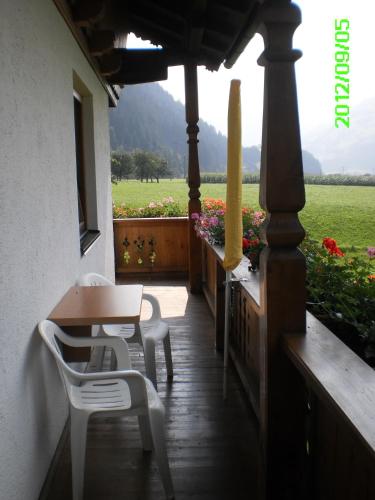 a porch with a table and chairs and a field of flowers at Haus Weitenstich in Zell am Ziller