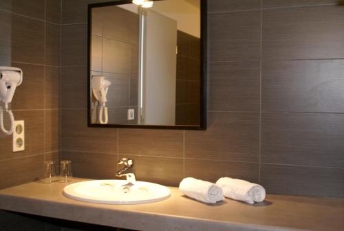 a bathroom with a sink and a mirror and towels at Hôtel Bar le Globe in Saint Die