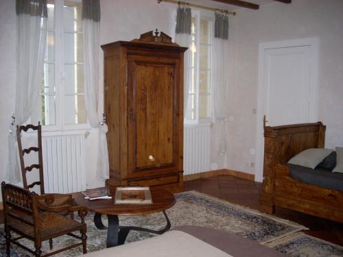 a living room with a bed and a table and chairs at Sous les Marronniers in Petit-Palais-et-Cornemps
